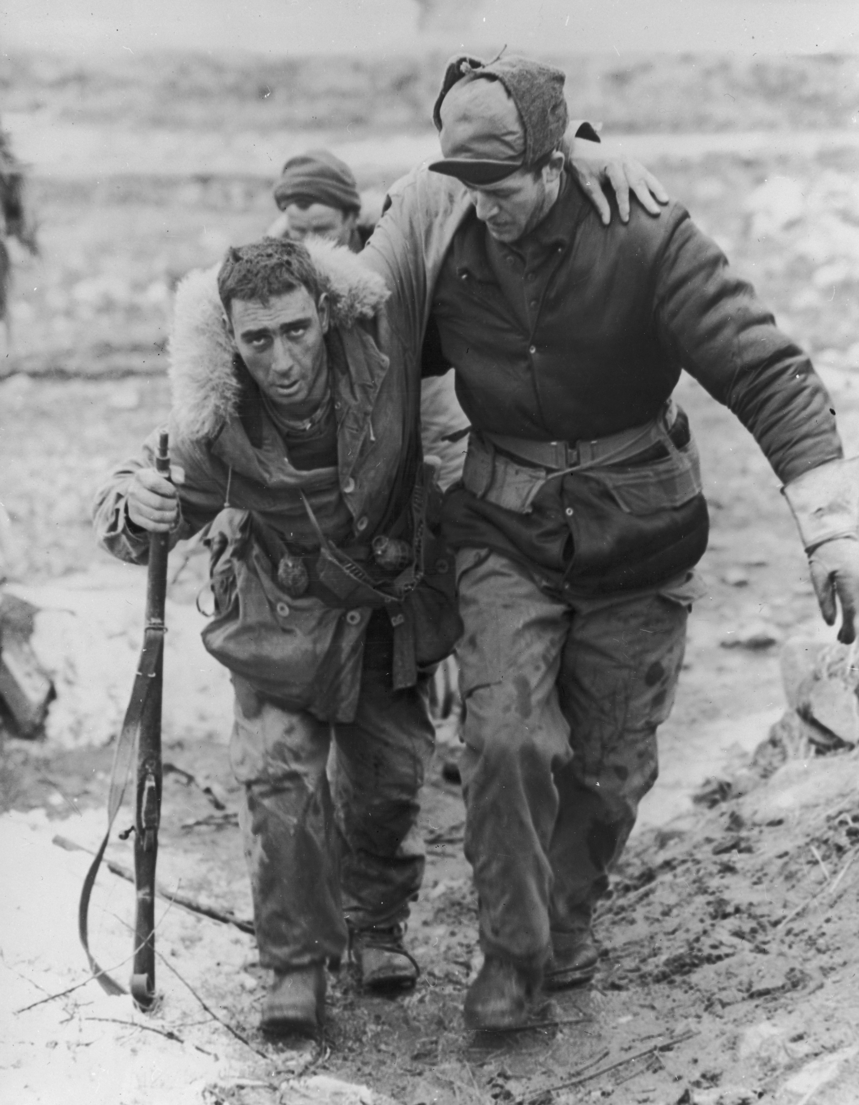 A United Nations soldier in uniform helps a wounded Canadian rifleman to an aid station behind the front lines during the Korean War/Hulton Archive/Getty Images