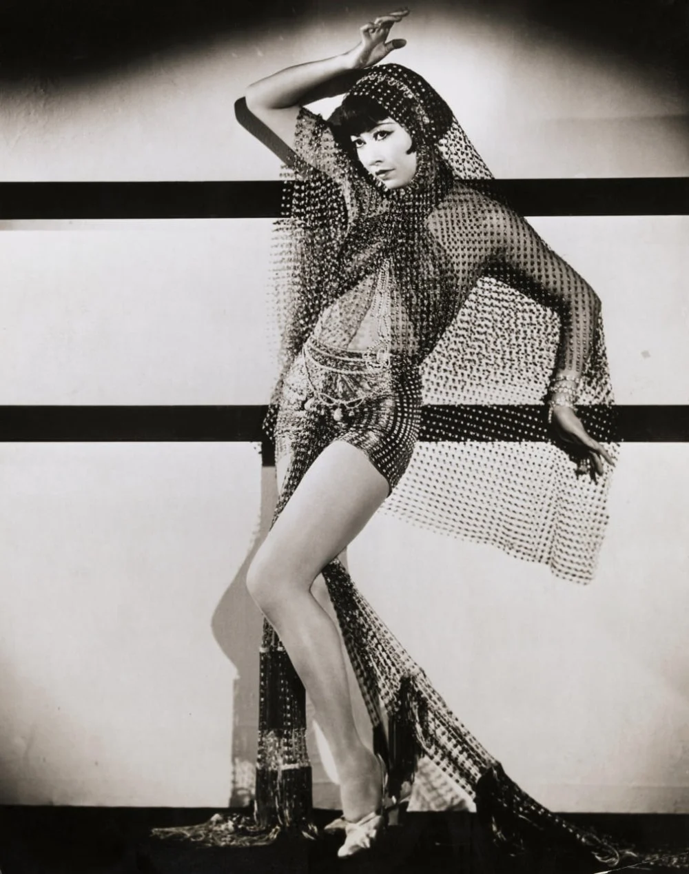 Chinese-American actress Anna May Wong strikes a dancer's pose in a costume of veils. Photograph circa 1920s/Getty Images