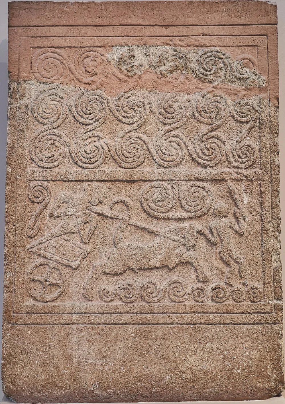  Funerary stele made of poros stone, with relief chariot scene. The upper and lower panels are filled with spirals, while the central panel has a chariot pulled by a galloping horse and driven by a standing charioteer. In front of the horse is a second male figure that appears to be attacking the chariot with the spear held in his raised right hand. Mycenae, Grave Circle A, Grave V, 16th cent. B.C. Inv. no. 1429. National Archaeological Museum of Athens./Wikimedia commons