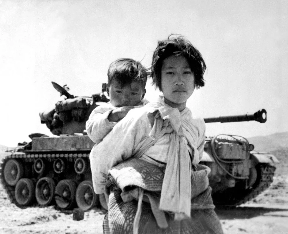 Кореянка с ребенком, а на заднем плане танк/ Getty Images