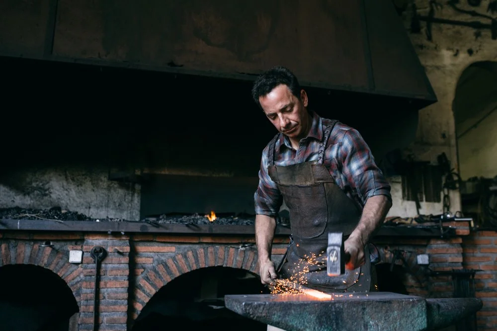 Blacksmith Hammering Hot Iron. Toledo, Spain/Inuk Studio/Stocksy