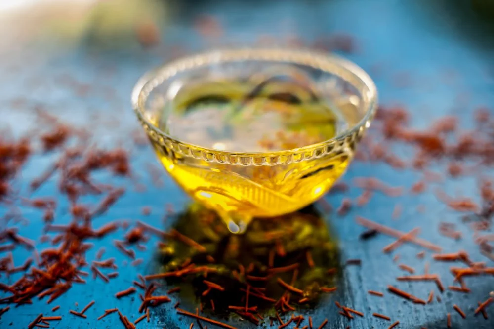 Saffron soaked in a glass bowl on a black surface with raw saffron threads/Kesar/Shutterstock