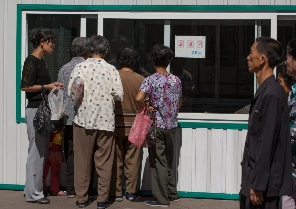 Северокорейцы стоят в очереди в уличном магазине. Пхеньян, Северная Корея/Alamy