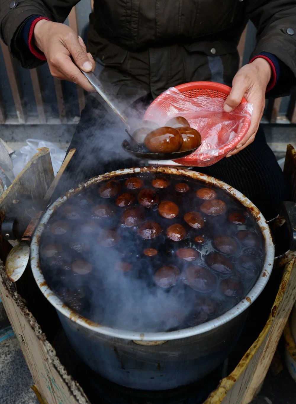 A local woman cooking traditional Tea leaf eggs. The eggs are cooked in tea, Soy sauce and other spices and are a common all over China/Alamy