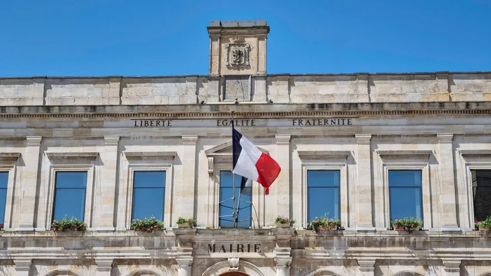 Флаг Франции на фасаде старинного здания мэрии с национальным девизом "Свобода, Равенство, Братство". Город Гравлин/Alamy