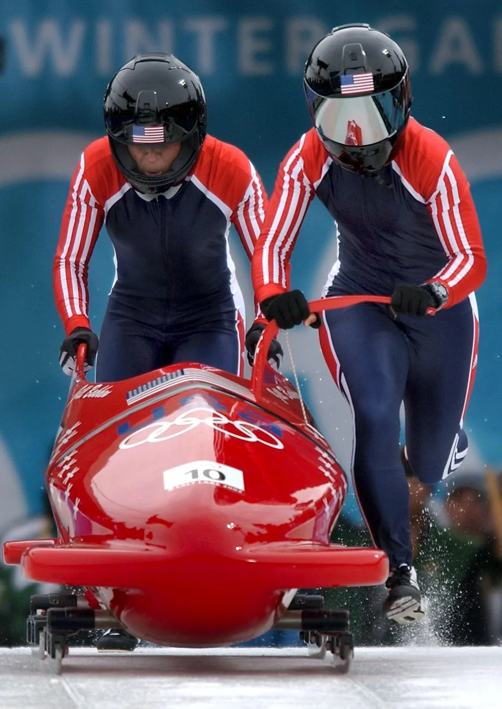 Vonetta Flowers (left) and Jill Bakken power up in the push zone for their 80-mile-per-hour (130 km/h) ride down the Winter Olympic bobsledding track. Bakken, the driver, and Flowers, the brakeman, won the first gold medal presented in Olympic women's bobsledding (2002)/the United States Navy/Wikimedia Commons